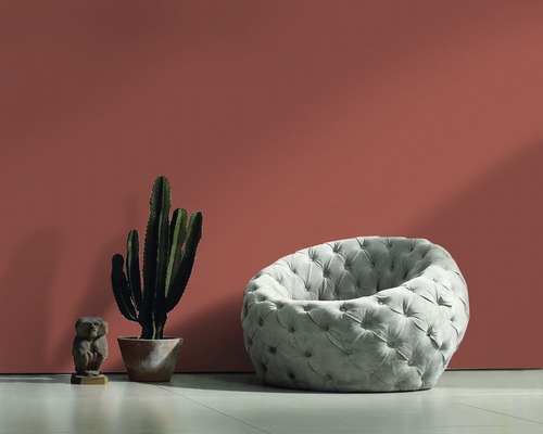 Fauteuil gris capitonné, cactus et figurine en bois