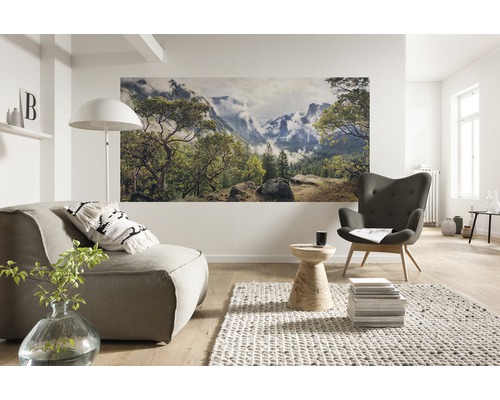 Salon lumineux avec fauteuil, canapé et peinture murale avec motif nature