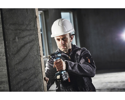Un homme portant un casque de sécurité perce une pièce à l''aide d''une perceuse sans fil.