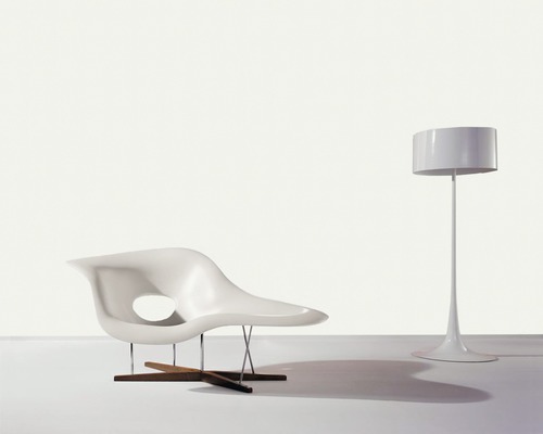 Scène avec fauteuil lounge en plastique avec structure en bois et en métal et un lampadaire.