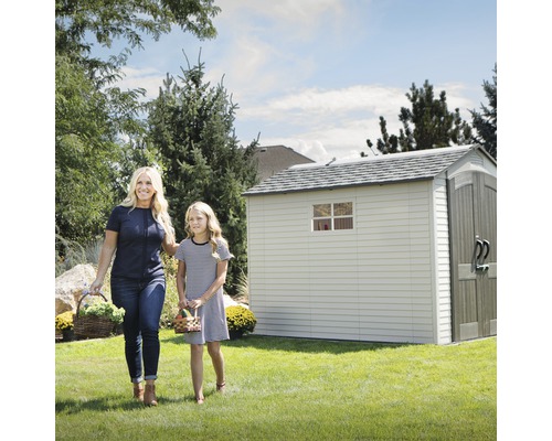 Une femme et une fille avec des paniers devant une remise de jardin dans le jardin.
