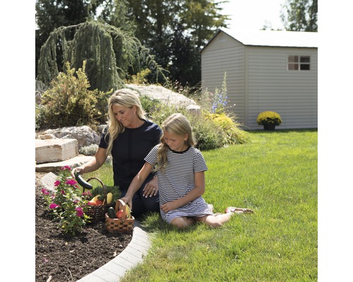 Mère et fille récoltent des légumes dans le jardin avec une remise de jardin