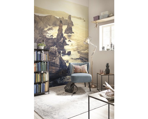 Wohnzimmer mit Fototapete einer Küstenlandschaft, Sessel, Stehlampe und Bücherregal