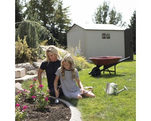 Scène de jardin avec abri de jardin, brouette, arrosoir et deux personnes plantant des fleurs