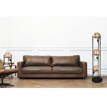 Wohnzimmer mit braunem Ledersofa und Stehlampe mit mehreren Glühbirnen