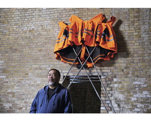 Plusieurs gilets de sécurité sur un porte-vêtements devant un mur de briques