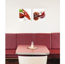Zwei Wandbilder mit Chili-Motiven über einem Tisch