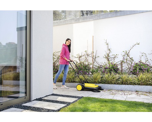 Femme utilise une balayeuse pour nettoyer une terrasse