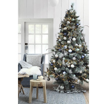 Sapin de Noël décoré avec des lumières, des boules de Noël et des décorations rustiques dans un salon.