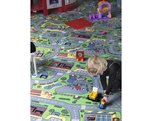 Enfant jouant avec des voitures jouets sur un tapis sur le thème de la ville