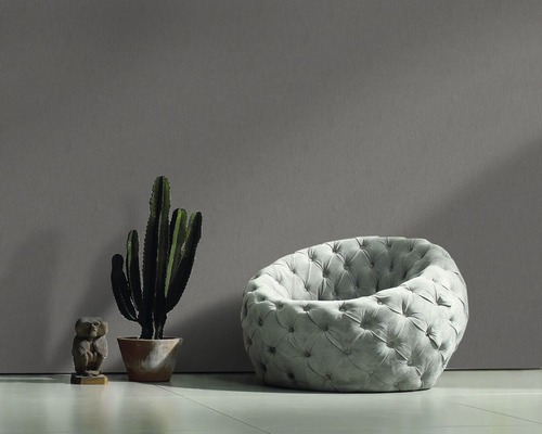 Scène avec un fauteuil rond capitonné, un cactus en pot et une petite sculpture.