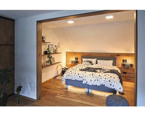 Schlafzimmer mit Bett, Nachttischen, Regalen und Holzelementen