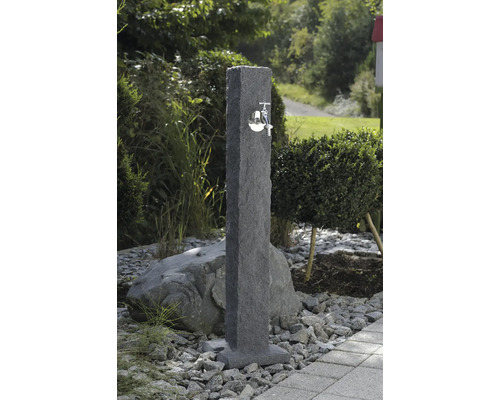 Scène de jardin avec une borne fontaine en pierre avec un robinet en métal.