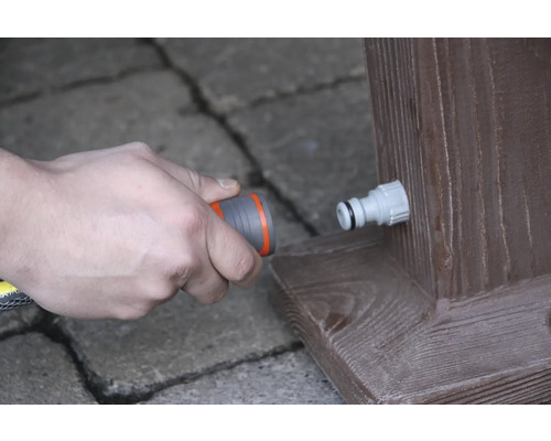 Raccordement d''un tuyau d''arrosage à un robinet sur une poutre en bois