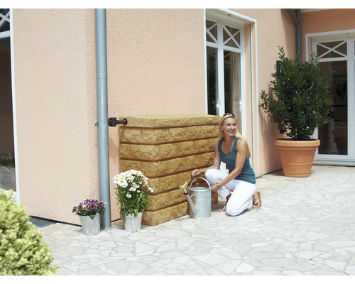Scène avec une femme agenouillée à côté d''un réservoir d''eau de pluie, avec des fleurs en pot et un arrosoir dans un jardin.