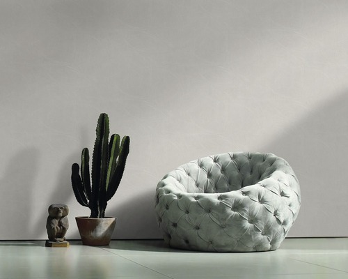 Scène avec un fauteuil capitonné, un cactus en pot et une figurine décorative.