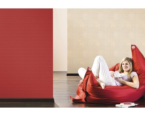 Femme se détend sur un pouf devant des papiers peints à motifs rouges et beige