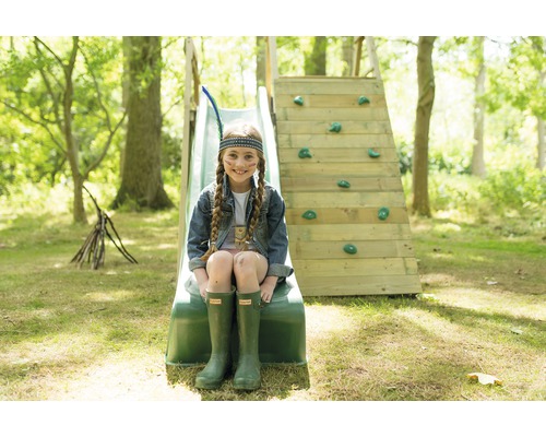 Mädchen sitzt auf einer Rutsche mit Kletterwand im Garten.