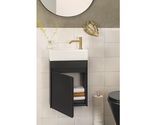 Badezimmer mit Waschbecken, Unterschrank mit offener Tür, Handtüchern, Toilette, Spiegel und Dekoration