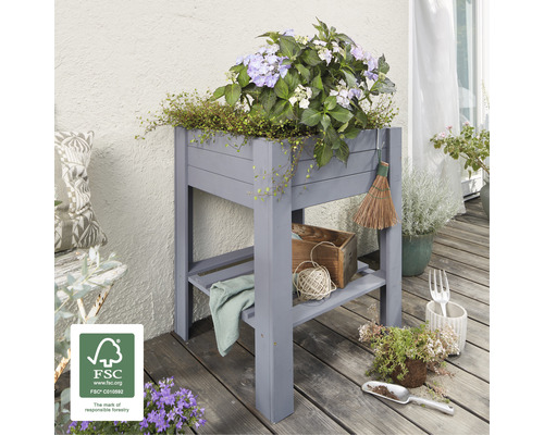 Hochbeet aus Holz mit Pflanzen und Gartenzubehör