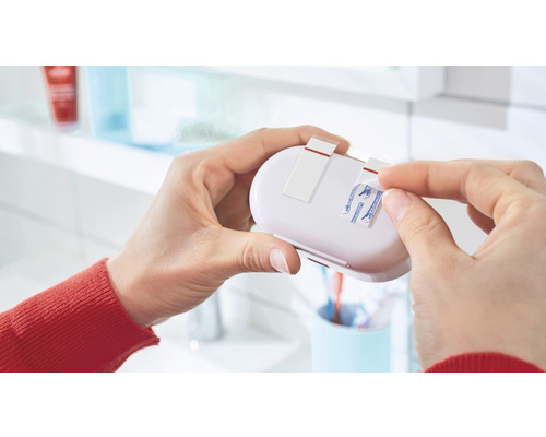 Person entfernt Schutzfolie von Klebestreifen einer Badezimmerablage