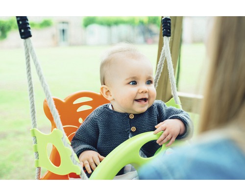 Bébé souriant dans une balançoire pour enfants avec des cordes