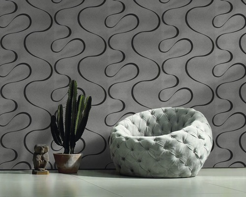 Aménagement de pièce avec papier peint à motifs, fauteuil, cactus et figurine décorative.