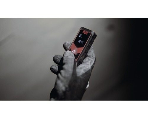 Une main avec un gant de travail tenant un télémètre laser.