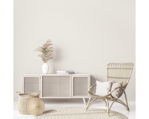 Wohnzimmer-Szene mit Kommode, Korbsessel, Teppich und Dekorationen für ein helles und freundliches Ambiente