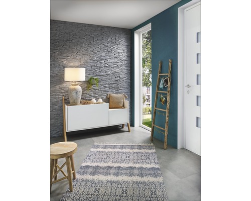 Espace de vie avec mur en pierre, commode, lampe, tapis et échelle en bois