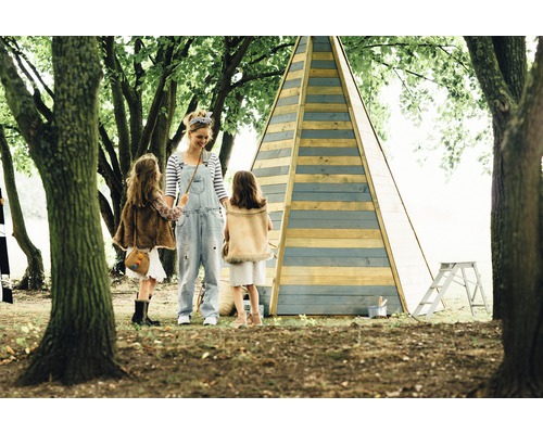 Mère avec deux enfants devant un tipi en bois dans le jardin