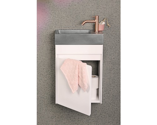 Meuble-lavabo avec vasque en béton, robinet et armoire ouverte avec serviette et papier toilette