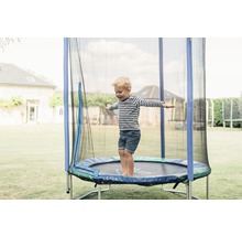 Garçon sautant sur un trampoline de jardin avec filet de sécurité