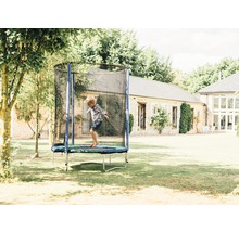 Enfant sautant sur un trampoline de jardin avec filet de sécurité.