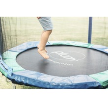 Un enfant saute sur un trampoline de jardin de la marque Plum.