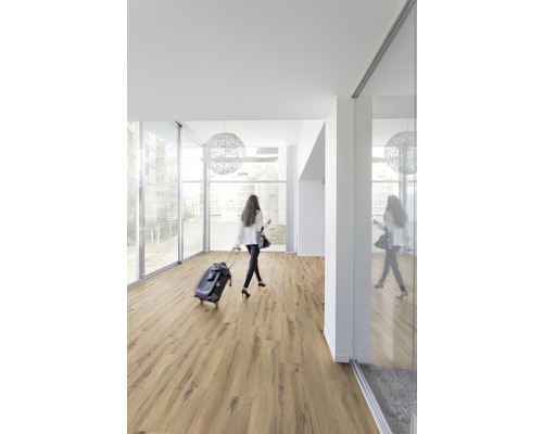 Pièce lumineuse avec sol stratifié et une femme avec une valise à roulettes