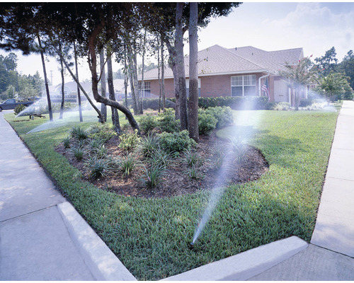 Système d''irrigation pour une pelouse et un jardin devant une maison.