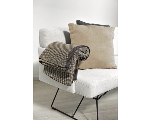 Beige Decke und Kissen auf einem hellen Sofa