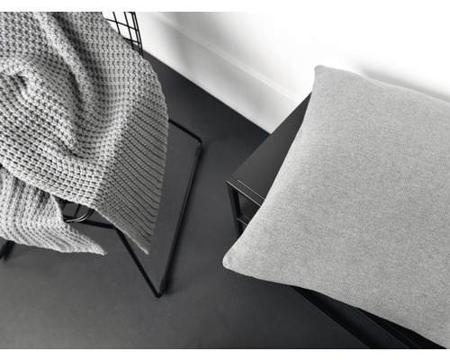 Dekoratives Arrangement mit Strickdecke und Kissen auf Ablage