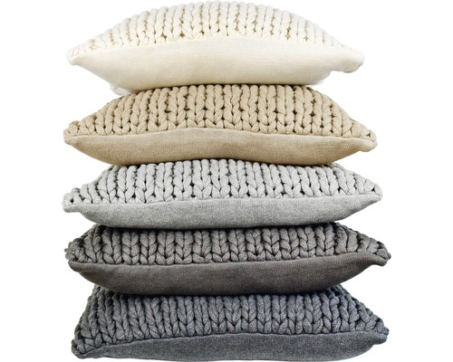 Stapel aus gestrickten Kissen in verschiedenen neutralen Farbtönen für die Inneneinrichtung