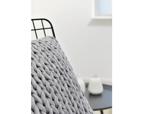 Nahaufnahme eines grauen Strickkissens auf einem Stuhl