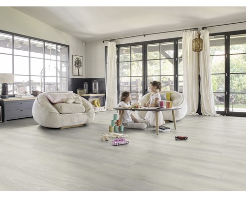 Pièce lumineuse avec sol en vinyle, fauteuils et enfants qui jouent.
