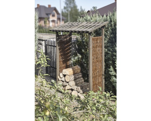 Abri à bois avec toit et parois latérales tressées dans le jardin.