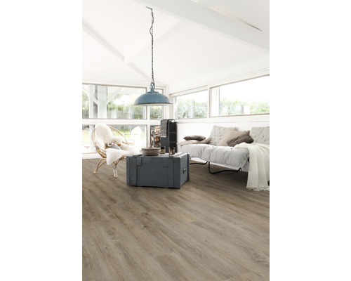 Pièce lumineuse avec sol stratifié, canapé, fauteuil et lampe