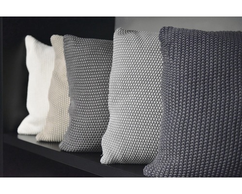 Mehrere Dekokissen aus Stoff auf einem Regal