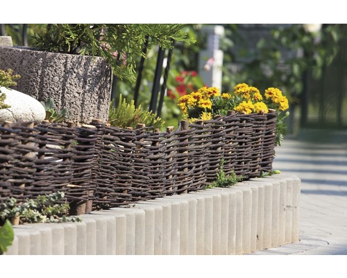 Bordure de parterre décorative en osier et pierres de béton dans le jardin.