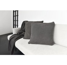 Zwei graue Kissen und eine Decke auf einem Sofa