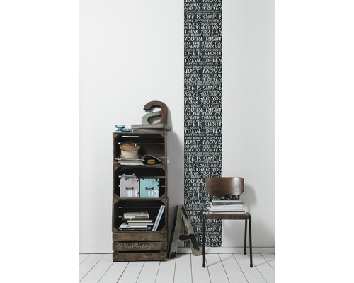 Raumgestaltung mit Holzkistenregal, Dekorationselementen und einer Wandtapete mit Schriftmotiven