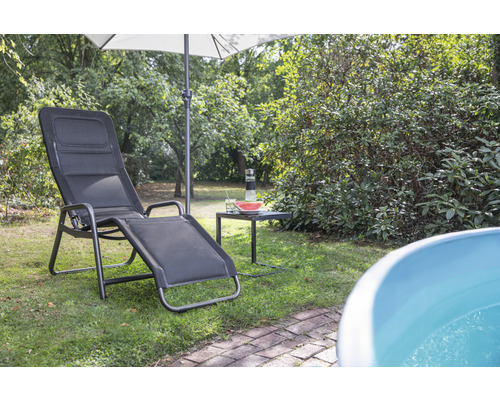 Scène de jardin avec une chaise longue, un parasol et une petite table avec des boissons et une pastèque.