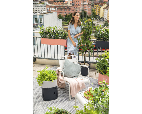 Balkonszene mit Frau, Stuhl, Pflanzgefäßen und Blick auf die Stadt